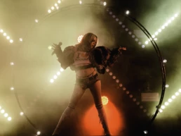 Dorian Electra performing at Best Kept Secret Festival in the Netherlands. They stand in a circular light rig wearing a distressed outfit and “I ❤️ Sodom” crop top, surrounded by fog and red-yellow stage lights. Photo by Marvin Anthony.