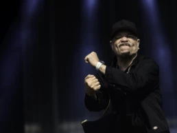 ce-T performing with Body Count at Graspop Metal Meeting in Dessel, Belgium. Captured mid-gesture with clenched fists, wearing a black LA cap and jacket under dramatic blue stage lighting. Photo by Marvin Anthony.