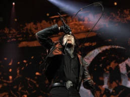 Will Gould of Creeper performing at Graspop Metal Meeting in Dessel, Belgium. He screams into the microphone with black face paint, red-stained mouth, and leather jacket under intense red lighting. A chaotic gothic backdrop completes the scene. Photo by Marvin Anthony.